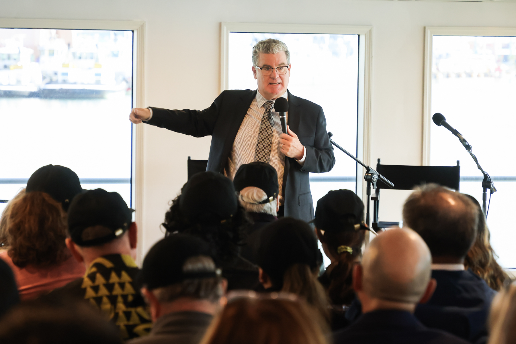 Photo of City Councilmember Tim McOsker speaking in front of a crowd aboard a boat