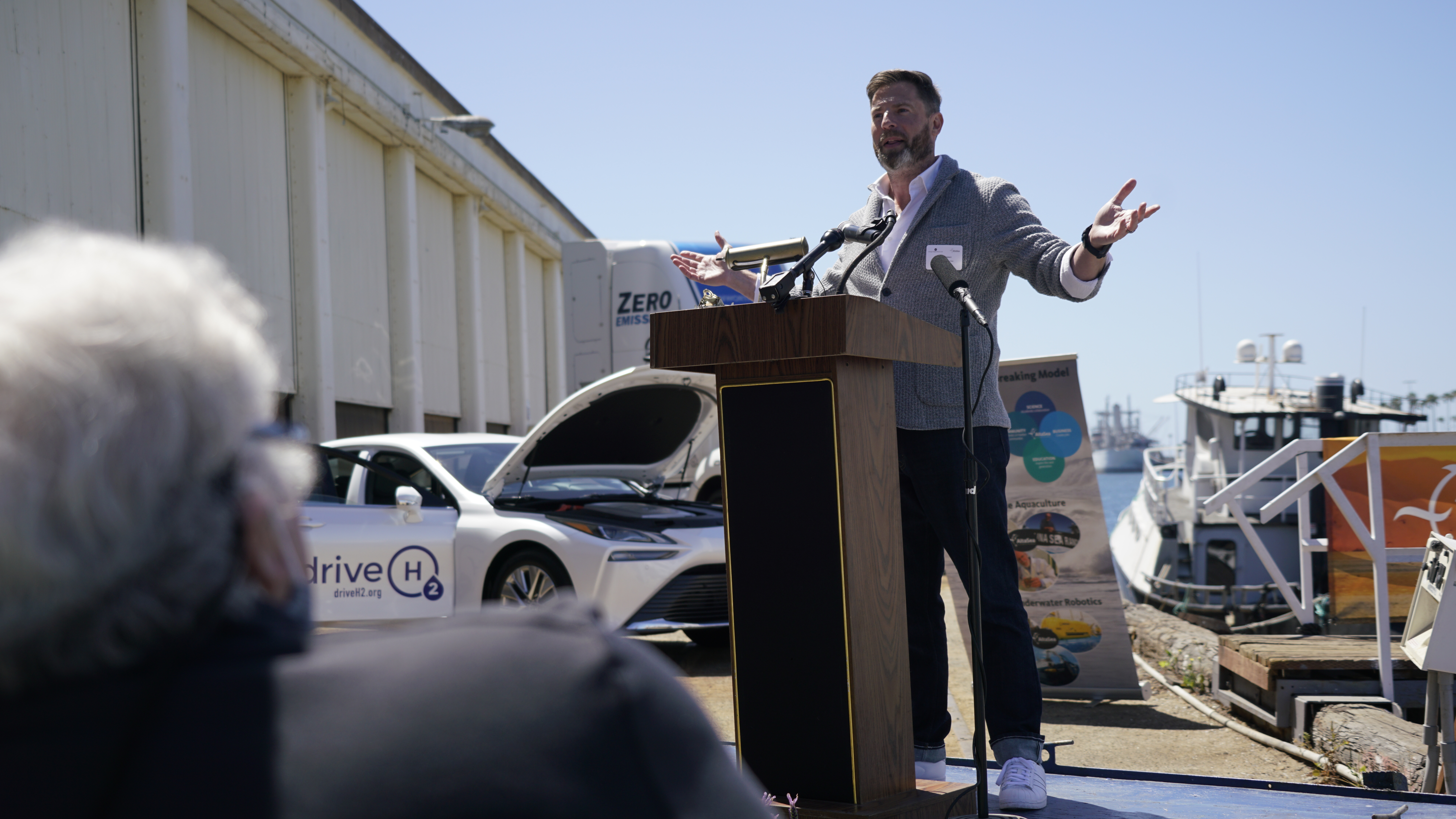 Brian Goldstein speaks to audience at AltaSea in front of fuel cell car & truck